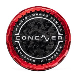 Close-up of a round red metal object with a black textured center and white text around the edge, forming a circular emblem/label