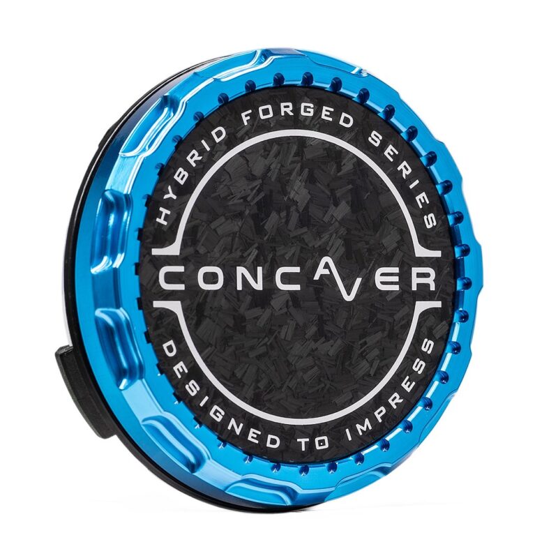 Blue metallic circular device with a textured black center and white ring text reading 'Hybrid Forged Series' and 'Designed to Impress' around the edge, with 'Conquer' branding in the middle.