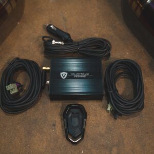 Black Valvetronic Designs amplifier on a brown carpeted trunk floor, with coiled power cables around it.