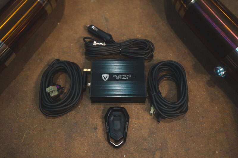 A7401078jpg - OPSHOLDERS Black Valvetronic Designs amplifier on a brown carpeted trunk floor, with coiled power cables around it.