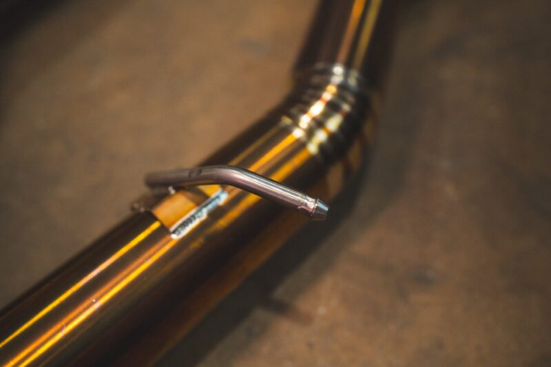 A7401083jpg - OPSHOLDERS Close-up of a bicycle wheel with a striped yellow rim and a metal valve stem in the foreground.
