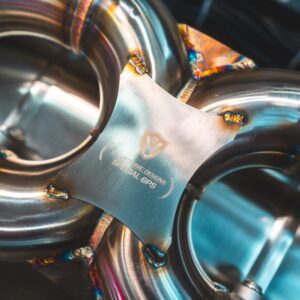 Close-up of welded stainless steel tubes with colorful heat marks in a mechanical assembly.