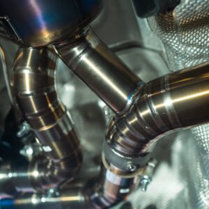 Close-up of polished stainless steel pipes and welded joints in a metallic machine interior.