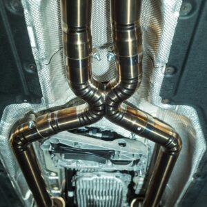 Underbody view of a car showing curved stainless steel exhaust pipes and heat shielding undercarriage