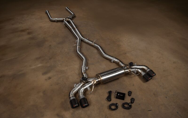 BMWF9XM5M8VSES_BR_RC_8jpg - OPSHOLDERS Stainless steel automotive exhaust pipes and mufflers laid out on a workshop floor with clamps and connectors visible