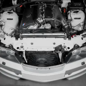 Front view of a white car with the hood open, showing the engine bay and a carbon-fiber intake manifold.