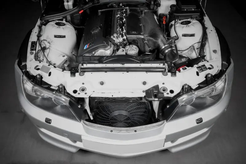 Front view of a white car with the hood open, showing the engine bay and a carbon-fiber intake manifold.