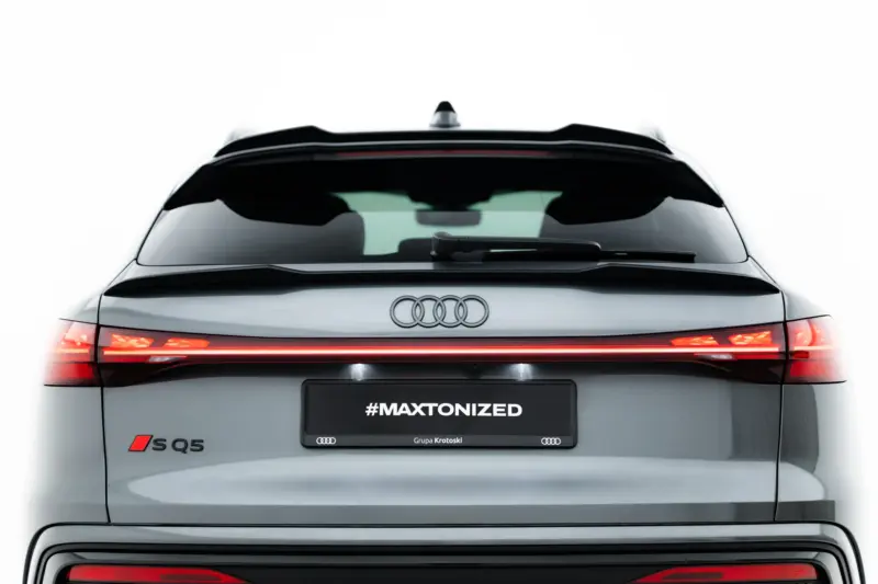 Rear view of a silver Audi SQ5 with red taillights and the license plate reading #MAXTONIZED, showing the Audi rings logo.