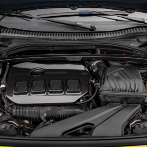 Front view of a car engine bay with carbon fiber components and a blue radiator cap visible on the left side.