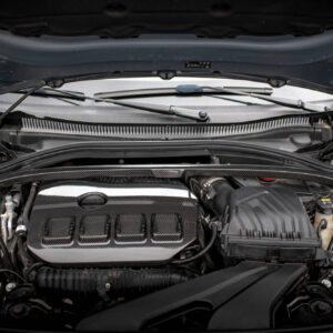 Open car hood revealing the engine bay with a carbon-fiber look intake, wiper arms, and various hoses and reservoirs in a sporty engine compartment.