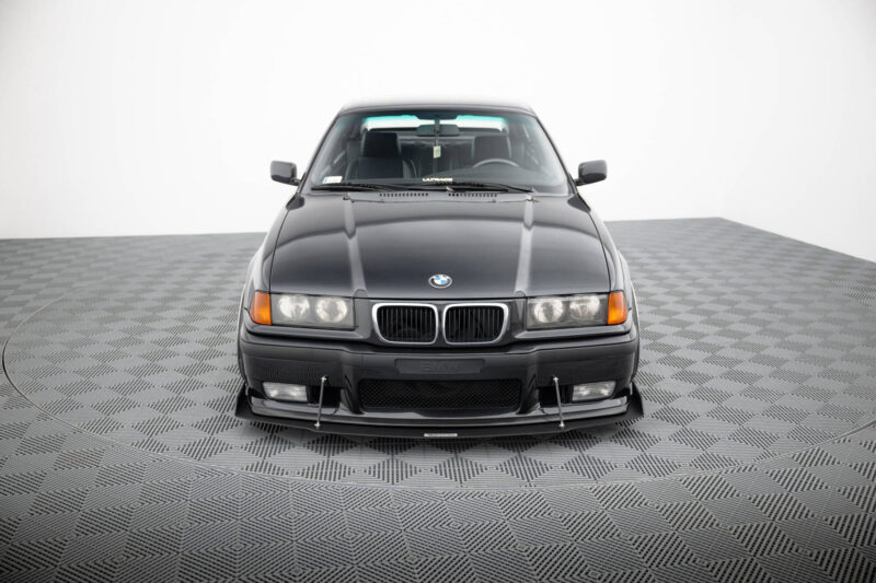 Front view of a dark gray BMW SUV in a studio with a checkered floor.