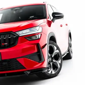 Red Škoda SUV shown from the front-left, highlighting the bold grille, headlight, and large black alloy wheels.