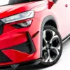 pol_po_Front-Bumper-Wings-Canards-Skoda-Kodiaq-RS-Mk2-23910_8webp - OPSHOLDERS Close-up of the front left corner of a red car, highlighting the angular LED headlight, black grille, and wheel with alloy rim.