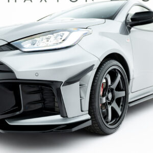 Close-up of a silver Toyota car's front left, featuring the headlight, grille, and wheel with a GR badge visible.