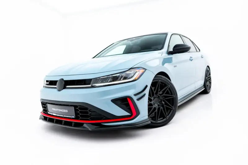Front-left angled view of a light-blue sporty sedan with large black wheels and a black front grille showing a VW badge and red accents at the bumper edge.