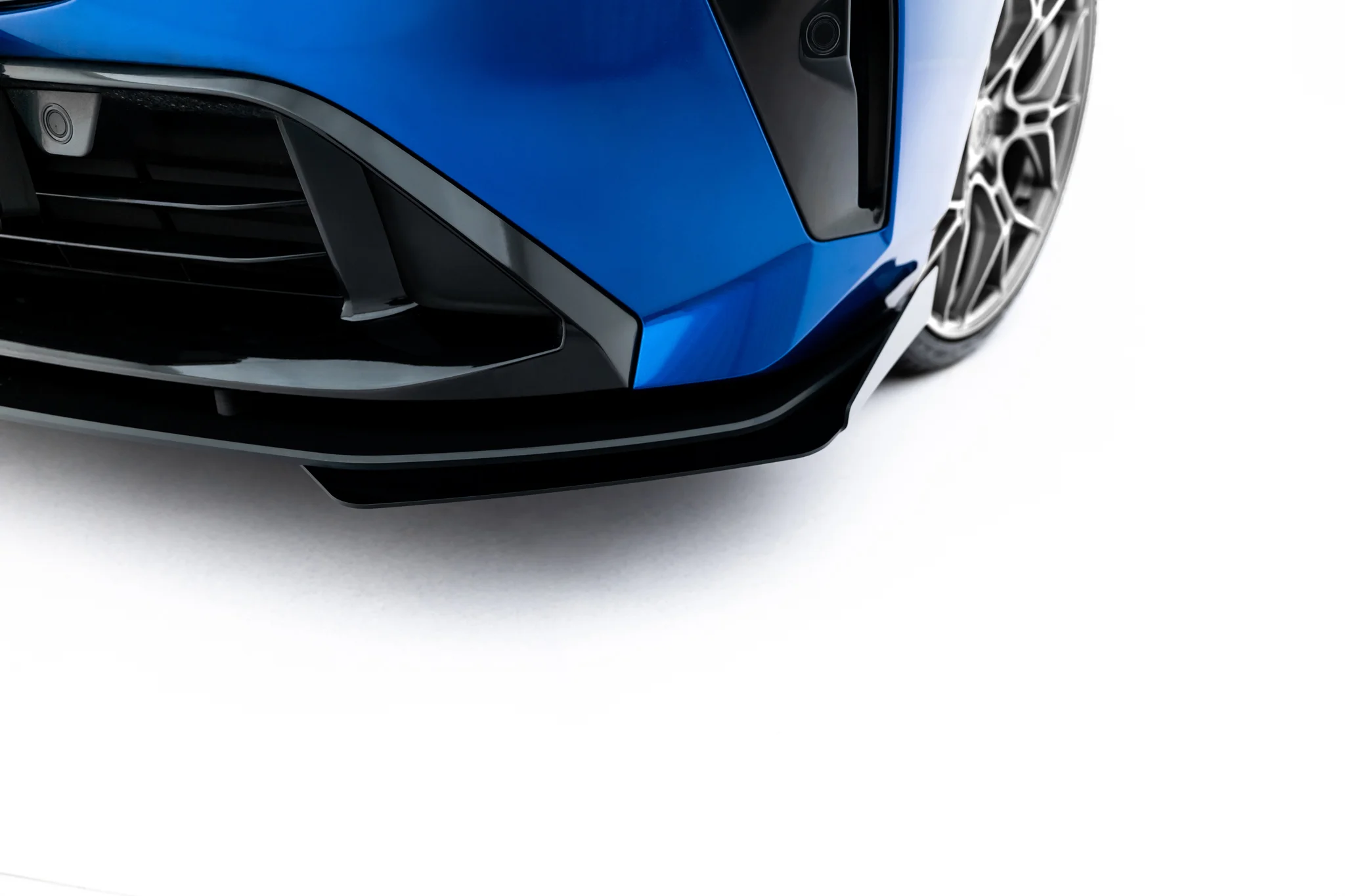 pol_po_Front-Flaps-Flaps-BMW-2-M-Pack-M235i-Gran-Coupe-F74-23839_2webp - OPSHOLDERS Close-up of a blue car's front bumper and wheel, showing glossy paint and intricate alloy rim against a white background.
