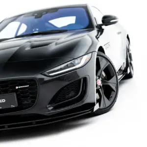 Close-up of a black Jaguar sports car’s front end, showing the grille, headlight, and Jag badge with '#MAXTONIZED' on the license plate area