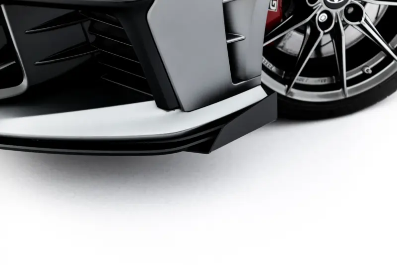 pol_po_Front-Flaps-Flaps-Toyota-GR-Yaris-Mk4-Facelift-23785_1webp - OPSHOLDERS Close-up of a sleek car front bumper with a silver lip and a large alloy wheel edge visible on the right side.