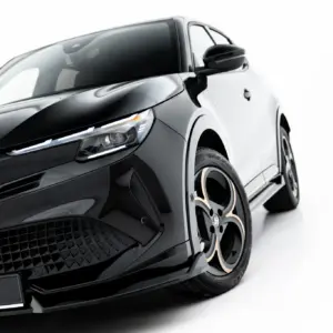 Close-up angled view of a glossy black car front, showing an LED headlight, grille, and alloy wheel with Alfa Romeo badge on white background.