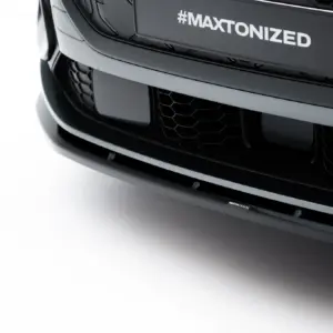 Close-up of a black car front showing a hexagonal grille and a license plate area reading '#MAXTONIZED'
