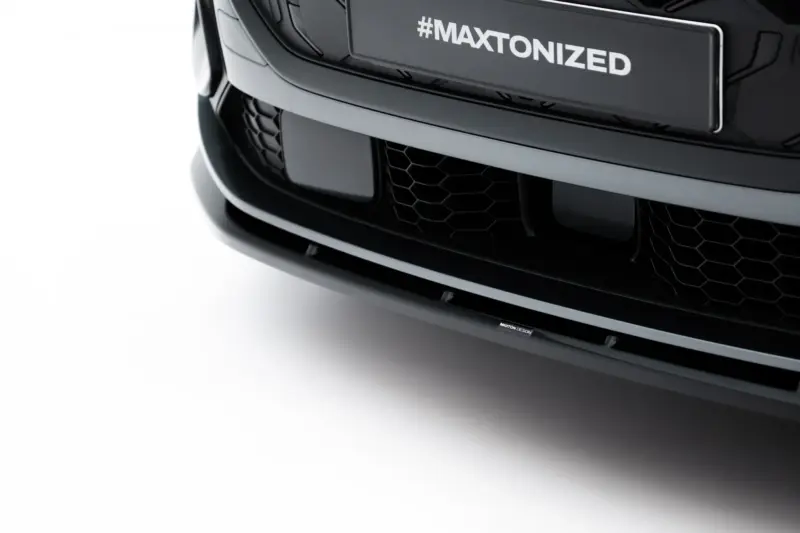 Close-up of a black car front showing a hexagonal grille and a license plate area reading '#MAXTONIZED'