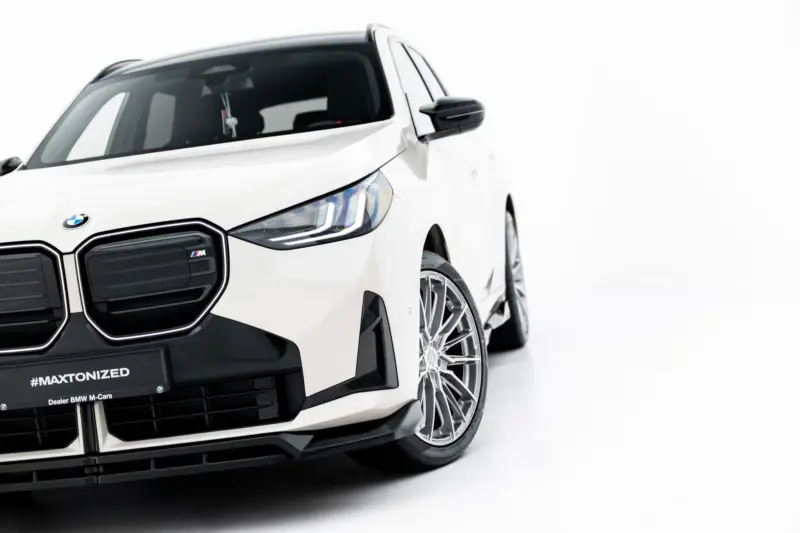Front-left angle of a white BMW SUV showing the distinctive kidney grille, headlight, and alloy wheel.