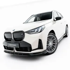 Front three-quarter view of a white BMW SUV in a bright studio, showing the prominent twin-kidney grille and large alloy wheels.