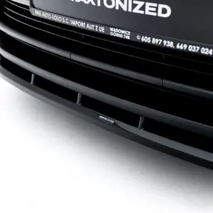 Close-up of a glossy black car front grille with curved horizontal slats and a small 'MAXTON DESIGN' badge
