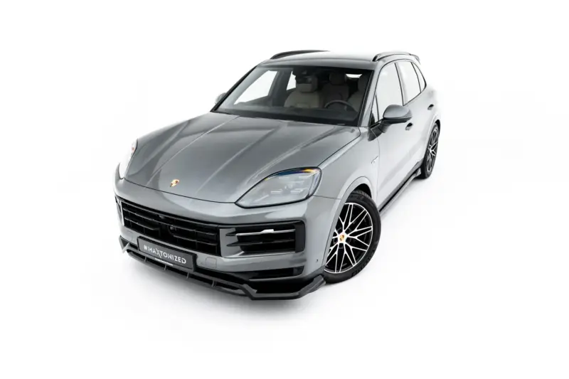 Front three-quarter view of a silver Porsche SUV with black grille and large alloy wheels against a white background in a studio-like shot.