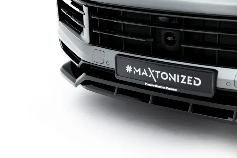 Close-up of a car front grille with a license plate reading '#MAXTONIZED' and 'Porsche Centrum Rzeszów' beneath it.