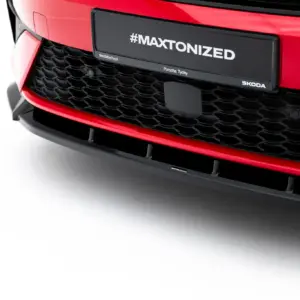 Close-up of a red car front with a black plate reading #MAXTONIZED and small branding text (Porsche Tychy, skodatychy.pl) on a honeycomb grille edge.
