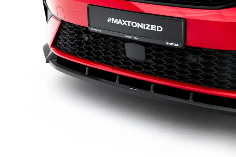 pol_po_Front-Splitter-Skoda-Kodiaq-RS-Mk2-23911_3webp - OPSHOLDERS Close-up of a red car front with a black plate reading #MAXTONIZED and small branding text (Porsche Tychy, skodatychy.pl) on a honeycomb grille edge.