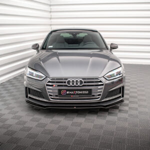 Front view of a gray Audi sedan in a modern, white-panel showroom with a checkered floor; license plate reads '#MAXTONIZED' Instagram tag.