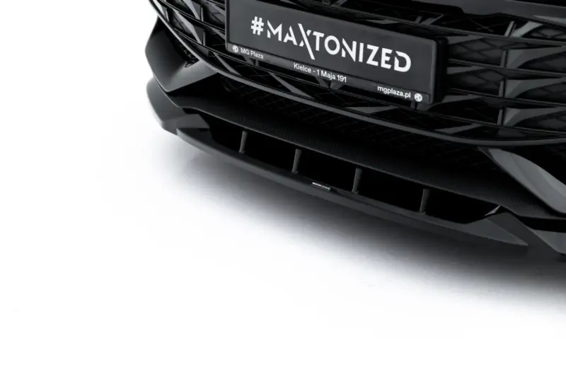 Close-up of a black car's front end with a glossy grille and a license plate reading '#MAXTONIZED'.