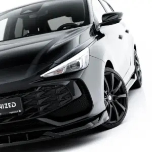 Close-up of a sleek black MG car front with prominent MG badge and a bold #MAXTONIZED license area, angled view showing headlight and grille.