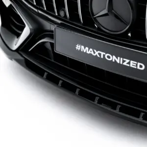Close-up of a black car grille with a license plate reading #MAXTONIZED on the front bumper.