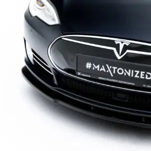 Front-close view of a black Tesla, showing the emblem and a plate reading #MAXTONIZED.