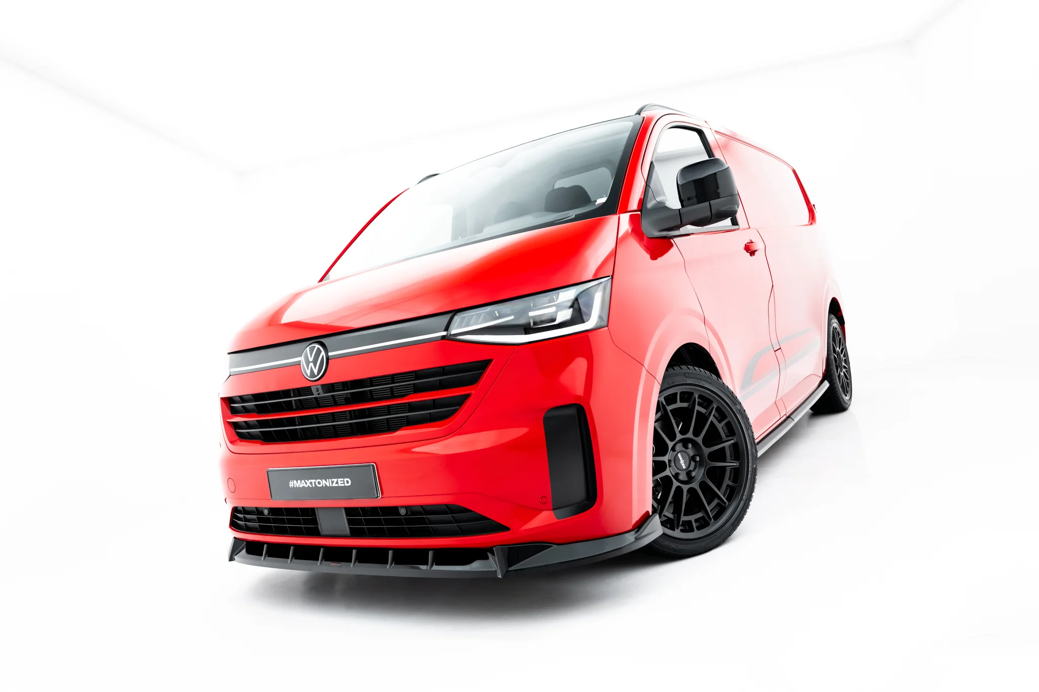 pol_po_Front-Splitter-V-1-Volkswagen-Transporter-T7-23937_3webp - OPSHOLDERS Red van angled from the front with black wheels and VW emblem, showing bold rugged design (#MAXTONIZED on plate).