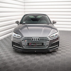 Front view of a gray Audi S5 in a bright, minimalist studio with striped walls behind it.