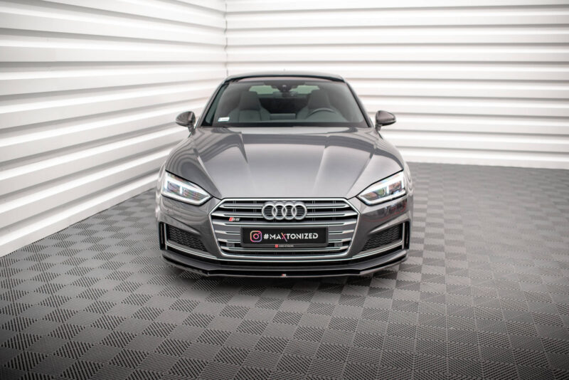 Front view of a gray Audi S5 in a bright, minimalist studio with striped walls behind it.