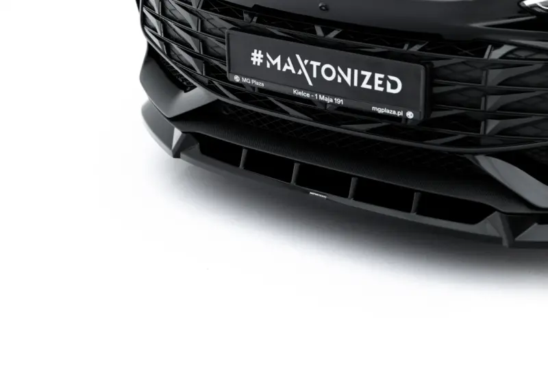 Close-up of a sleek black car front with a license plate reading #MAXTONIZED.