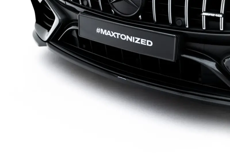 Close-up of a black car grille with #MAXTONIZED branding on the license plate area and AMG badge visible