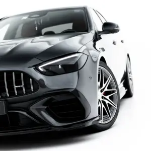 Front-left view of a sleek dark-gray Mercedes-Benz car, highlighting the distinctive grille and sharp headlight.