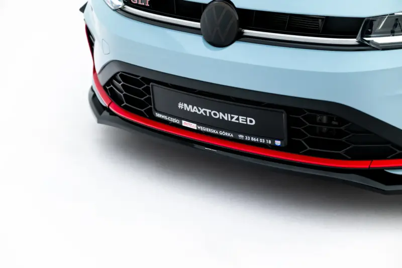 pol_po_Front-Splitter-V-2-Volkswagen-Jetta-GLI-Mk7-Facelift-2-23930_4webp - OPSHOLDERS Close-up of a light-blue car front featuring the VW emblem, black grille, and a license plate with the hashtag #MAXTONIZED.