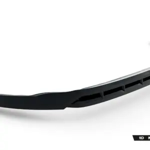 Curved black aftermarket car bumper lip spoiler with ribbed underside, shown diagonally across a white background (Maxton Design)