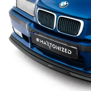 Close-up of a blue BMW front end, showing the kidney grilles and BMW emblem, with a license plate that reads '#MAXTONIZED'.