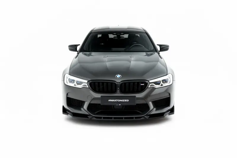 Front view of a gray BMW M5 with a black kidney grille and illuminated LED headlights on a white background, featuring the #MAXTONIZED plate area.