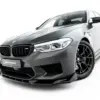 pol_po_Front-Splitter-V-3-BMW-M5-F90-23924_7webp - OPSHOLDERS Close-up of a silver BMW M5 front corner, showing the grille, headlight, and front bumper on a white background.