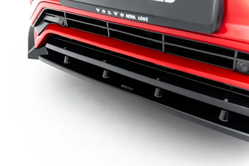 Close-up of a red Volvo front grille with black horizontal slats and the dealership text 'VOLVO NOVA ŁÓDŹ' above.