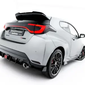 Rear three-quarter view of a gray sports car with a large black spoiler, red LED taillights, and exposed exhausts.